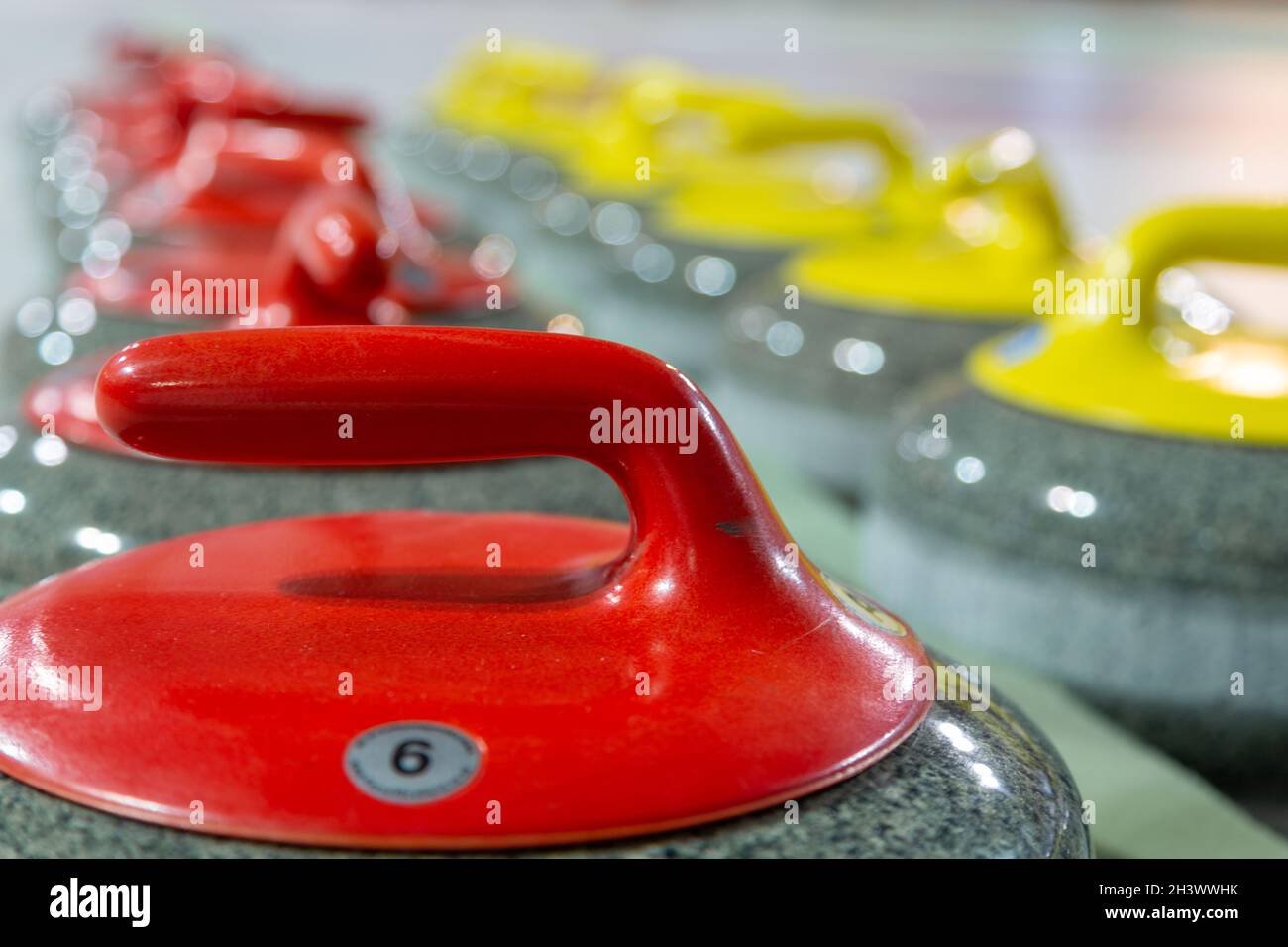 Curling Steine aus Granit ordentlich auf dem Spielplatz angeordnet. Lockensteine, selektiver Fokus. Stockfoto
