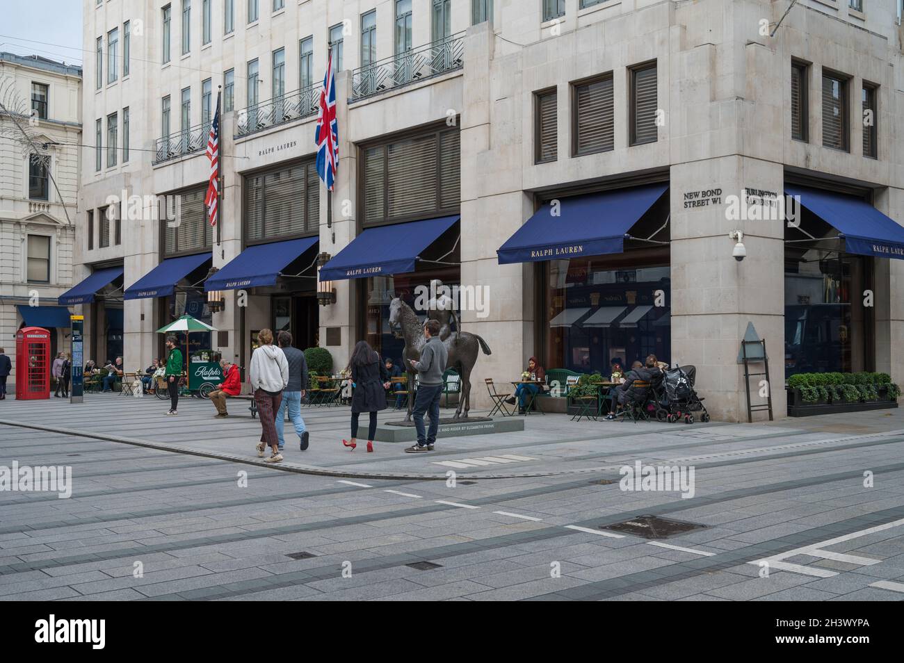 Menschen, die sich auf dem Straßenbelag vor dem Ralph Lauren-Laden, der New Bond Street, Mayfair, London, England, VEREINIGTES KÖNIGREICH Stockfoto