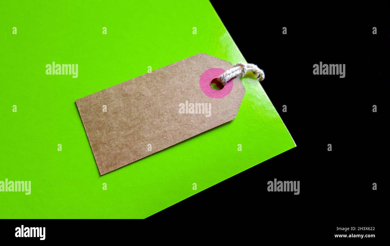 Preisschild oder Etikett aus braunem Karton auf grünem und schwarzem Hintergrund. Ansicht von oben Stockfoto
