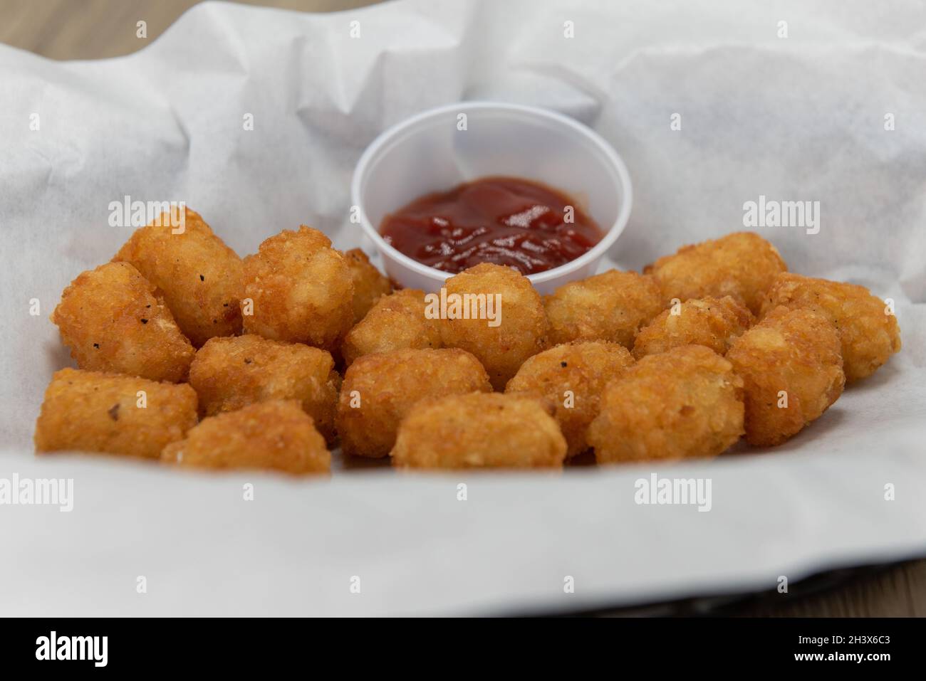 Vorspeise Bestellung eines Korbes mit knusprigen Tator Tots komplett mit Ketchup Dipping Sauce. Stockfoto