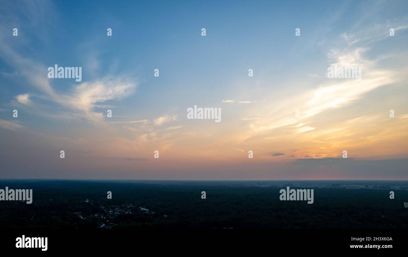 Farbenfroher Himmel im Hintergrund Sonnenuntergang, beleuchtete rosa-orange dramatische Wolken, Luftaufnahmen, weiter Horizont, untergehende Sonne. Ideal für Stockfoto