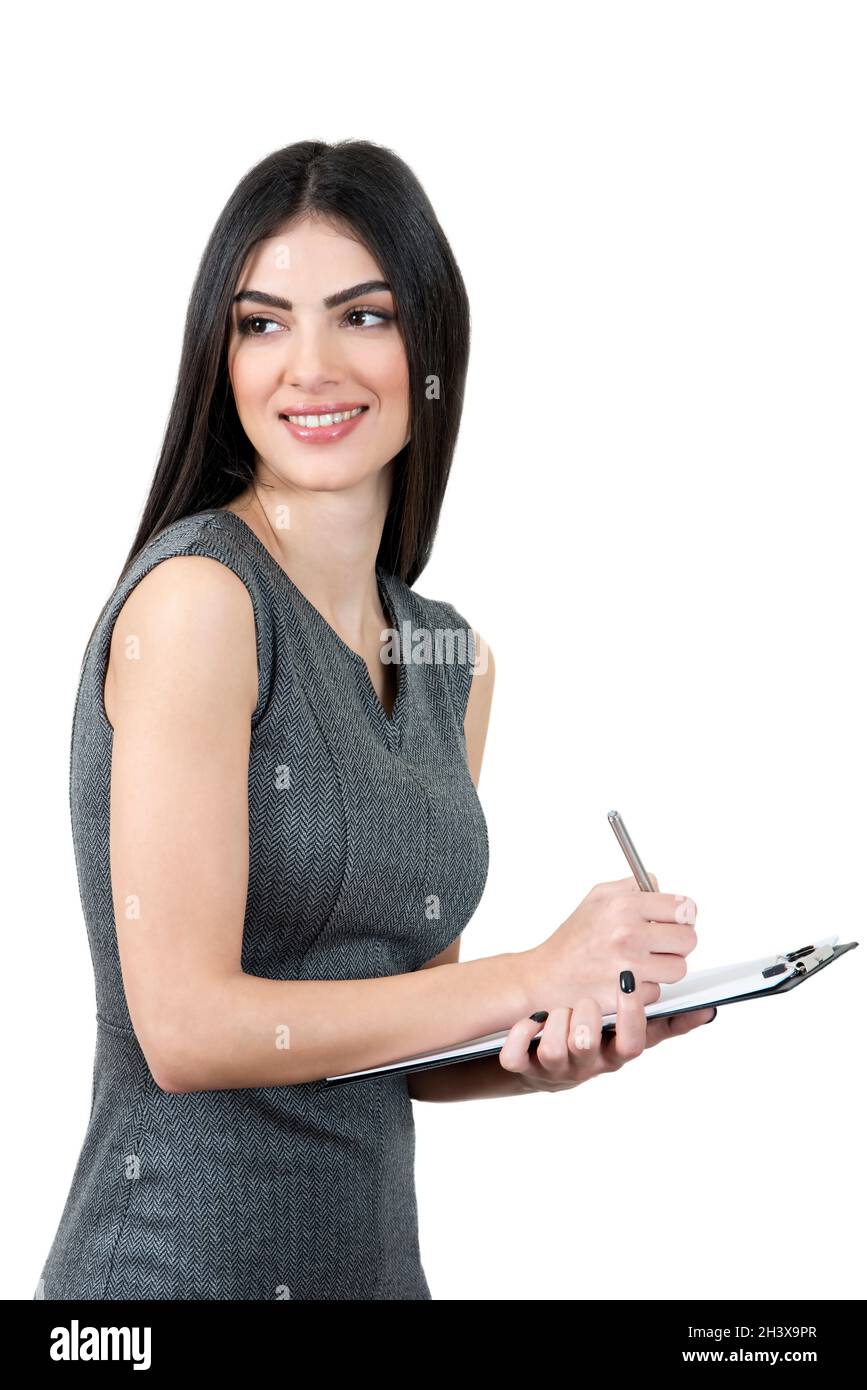 Junge Frau in einem grauen Kleid, mit einem Notizblock und Notizen. Sie schaut weg und lächelt. Stockfoto