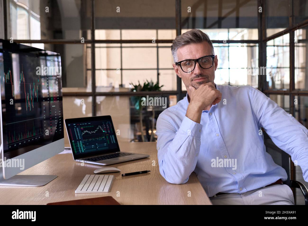 Serious männlich ceo Geschäftsmann Händler Blick auf Kamera am Schreibtisch mit pc-Computern. Stockfoto