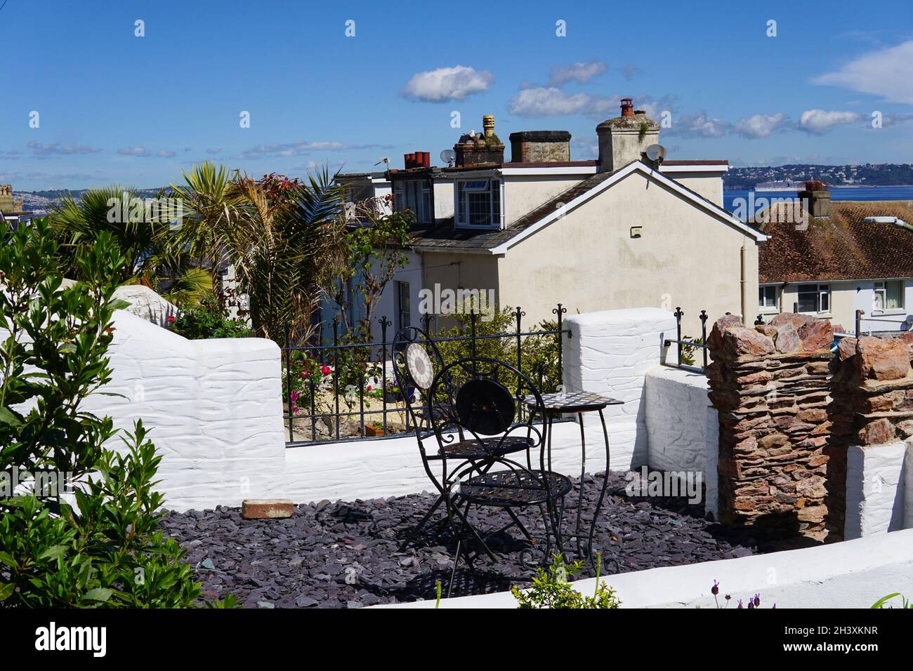 04. Juni 2021, Stühle und Tisch im Garten mit Meerblick in der Stadt Brixham an der Südküste von Devon, Sommerferienort. Stockfoto