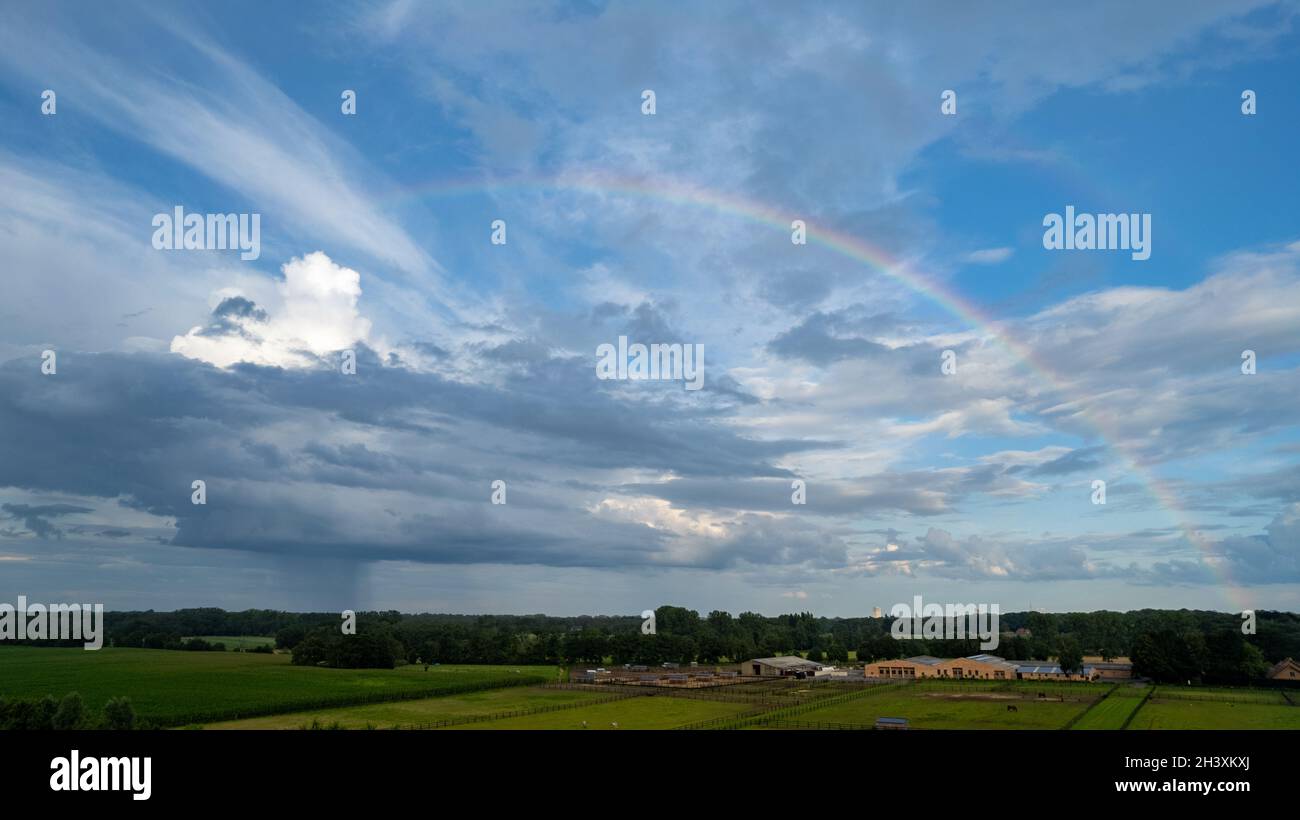 Luftaufnahme mit Drohne eines Regenbogens über stürmischem Himmel. Ländliche Landschaft mit Regenbogen über dunklen stürmischen Himmel in einer Landschaft bei Stockfoto