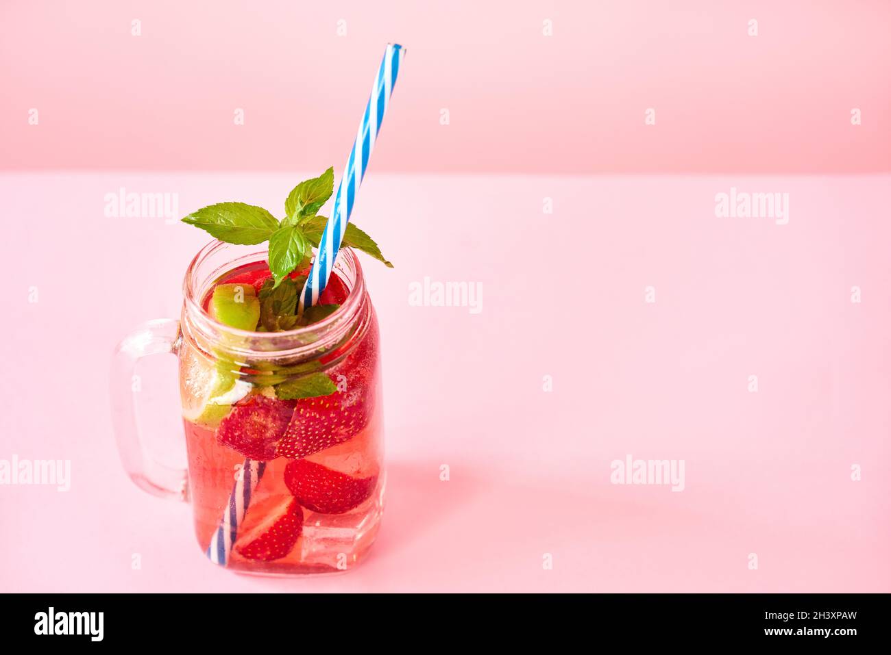 Erdbeere selbstgemachte Limonade in einem Einmachglas mit Kopierraum auf rosa Hintergrund. Stockfoto