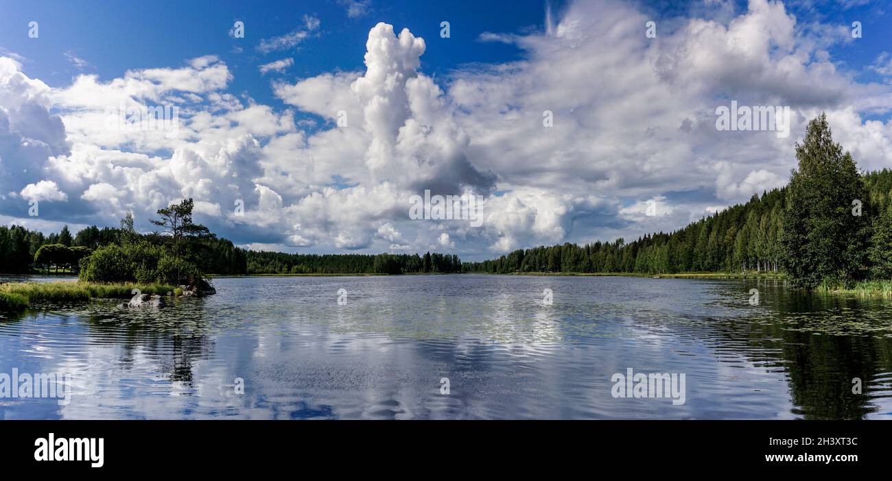 Friedliche idyllische Seenlandschaft mit üppig grüner Sommervegetation unter blauem Himmel mit weißen Wolken Stockfoto