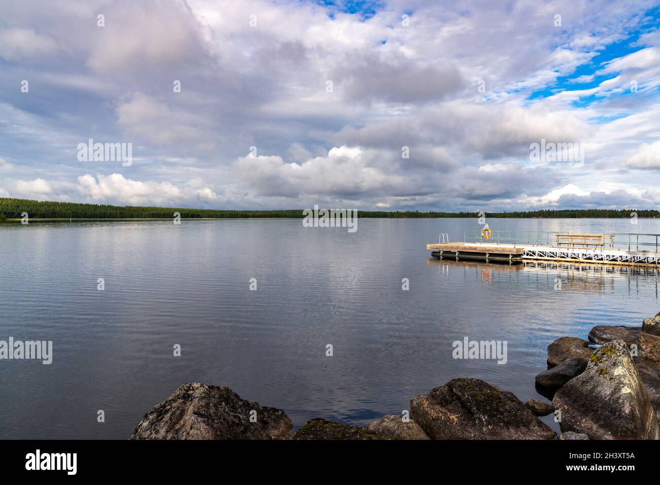 Ein hölzerner schwimmender Dock und eine Schwimmplattform am Ufer eines ruhigen und friedlichen Sees Stockfoto