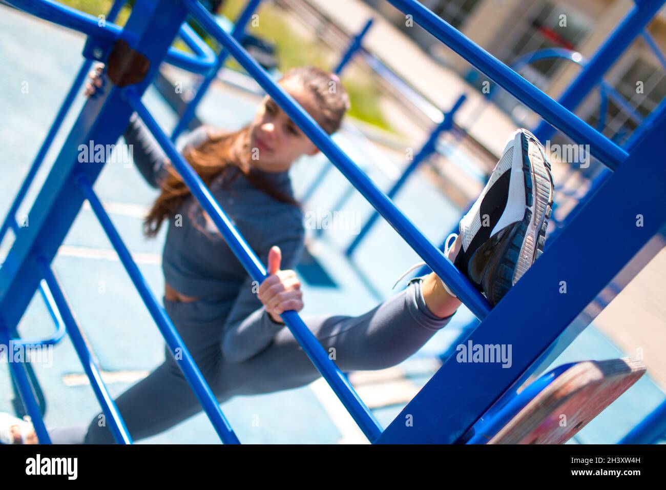 Junge schlanke Frau, die Garn macht, um die Beine zu strecken. Positive Mädchen tun die Splits im Freien. Stockfoto