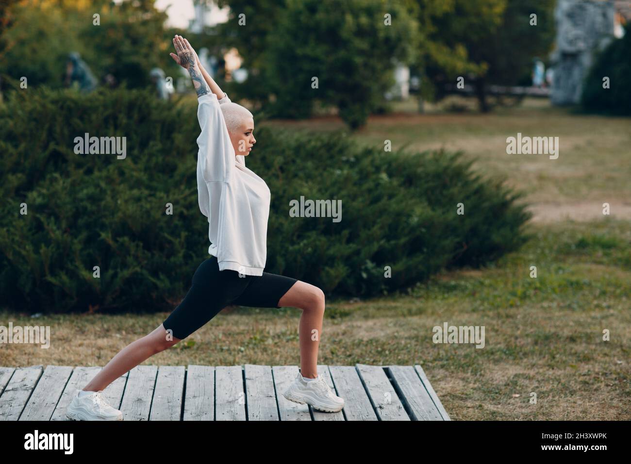 Milenial junge Frau blonde kurze Haare tun Yoga im Freien Stockfoto