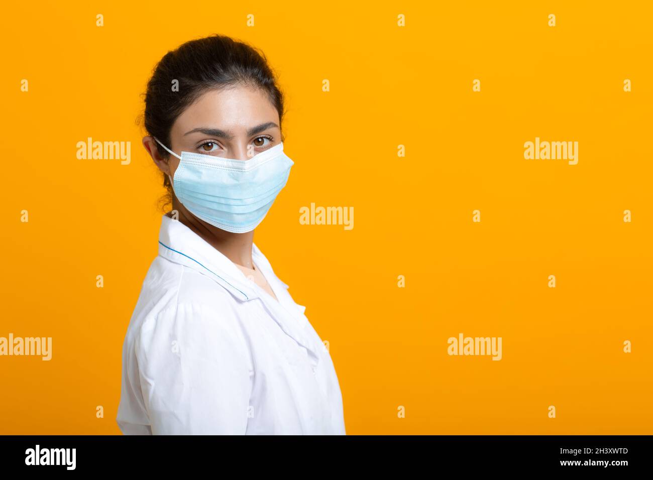 Porträt der indischen Ärztin in weißem medizinischen Kleid isoliert auf gelbem Hintergrund Stockfoto