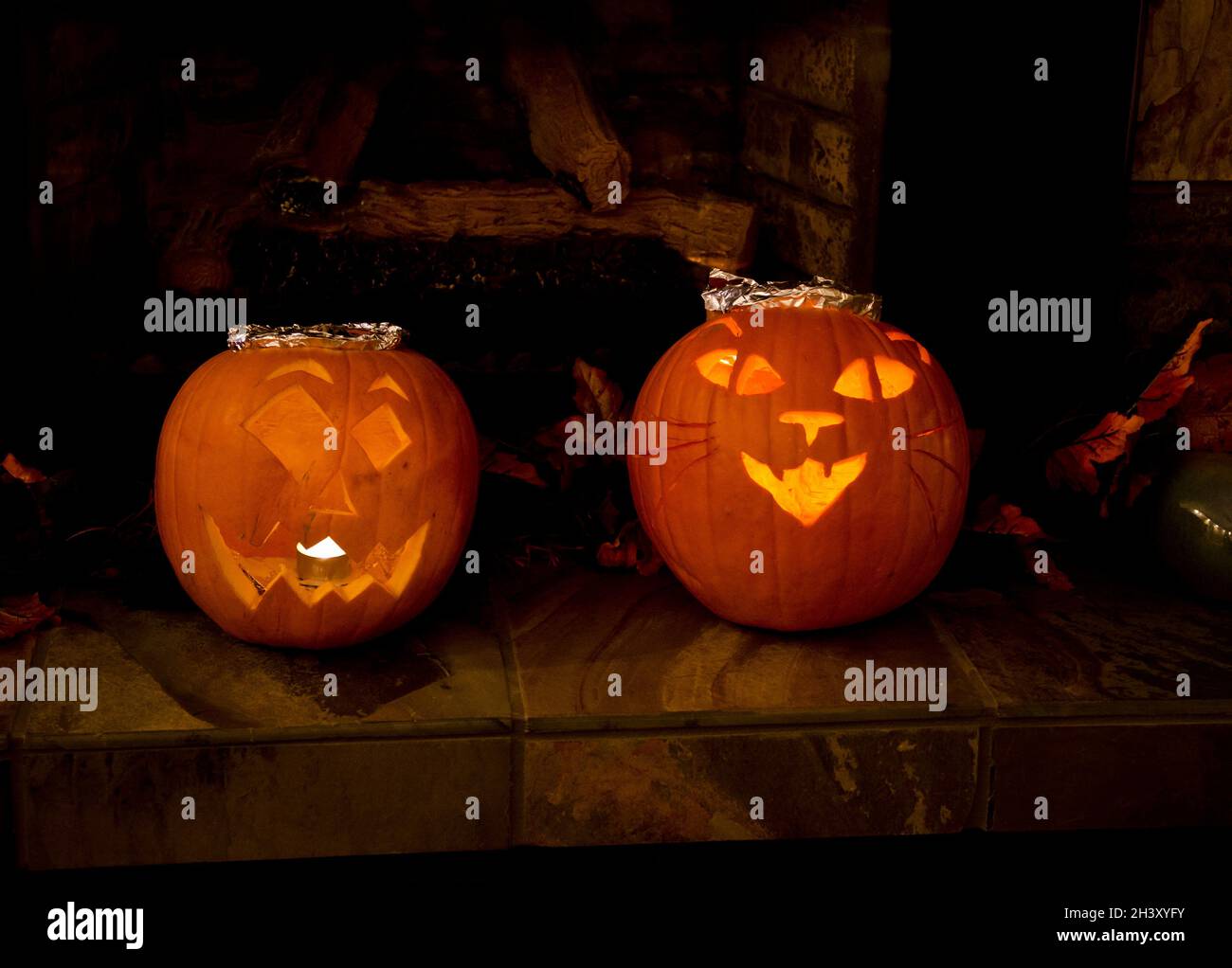 Zwei geschnitzte Halloween Kürbisse zu Hause, einer mit einem Katzendesign. Beleuchtete Jack O Laternen im Haus für Halloween. Stockfoto