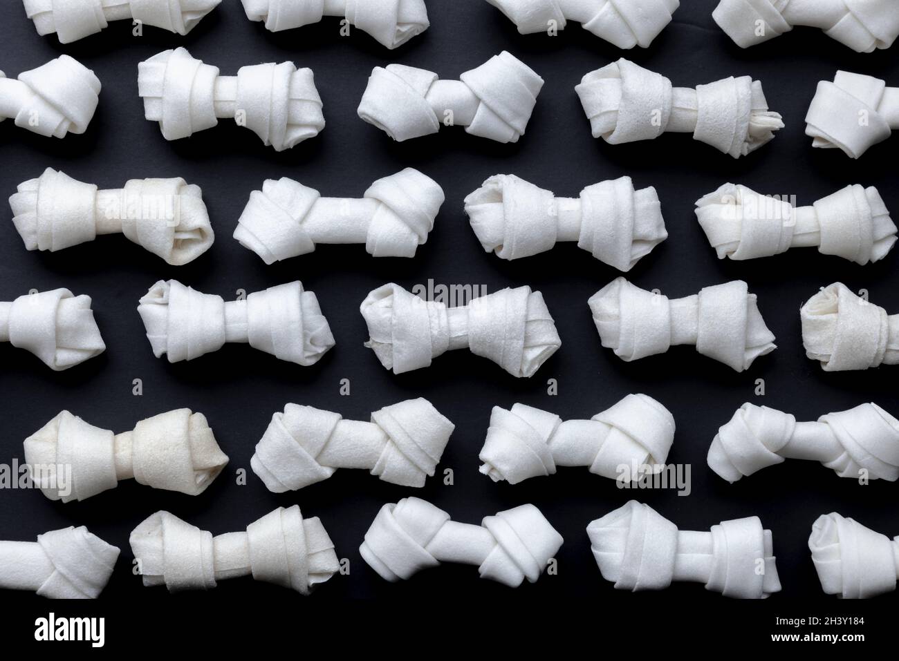 Mehrere kleine Rawhide Dog Chew Bones auf schwarzem Hintergrund Stockfoto