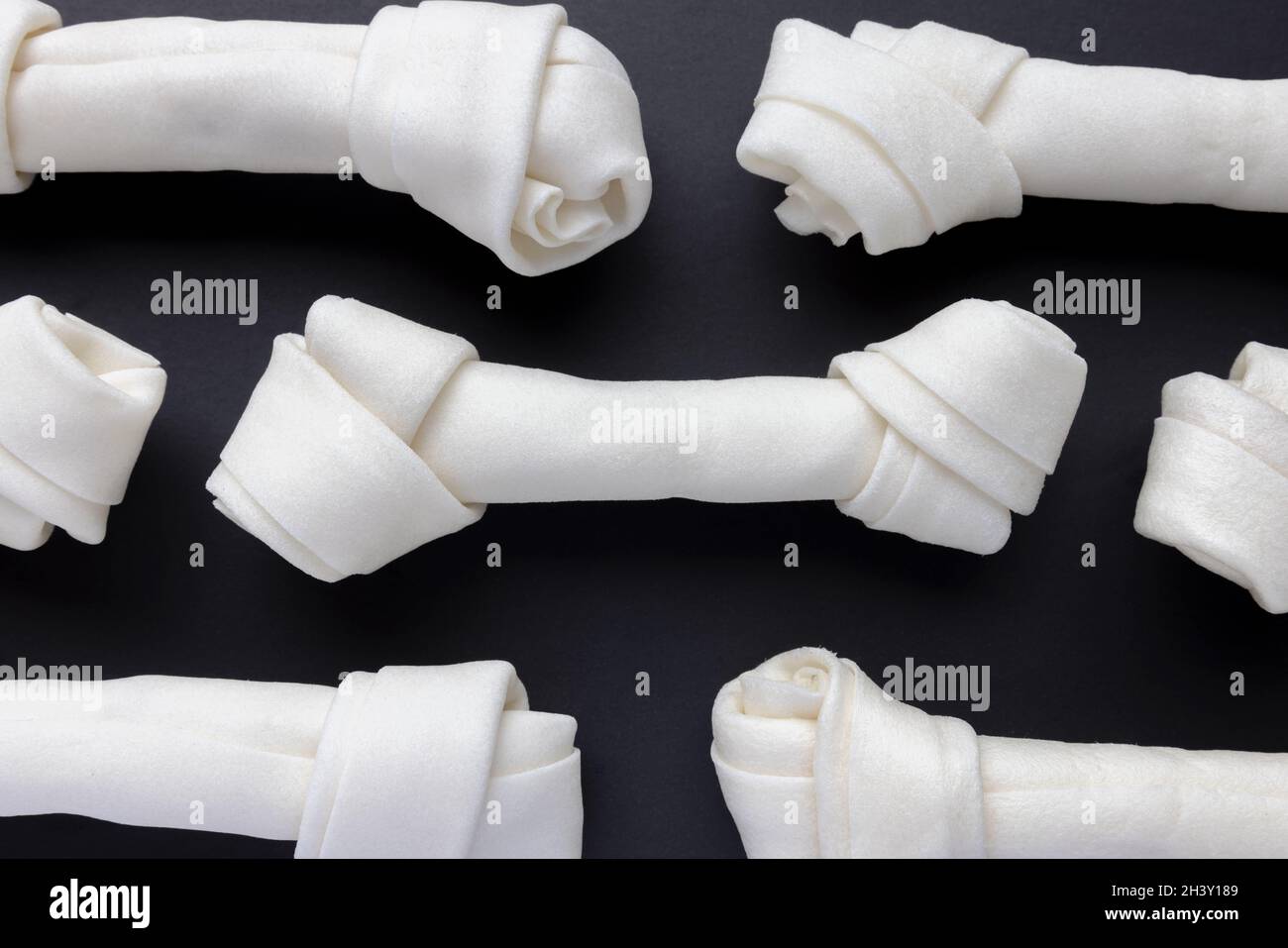 Mehrere große Rawhide Dog Chew Bones auf schwarzem Hintergrund Stockfoto