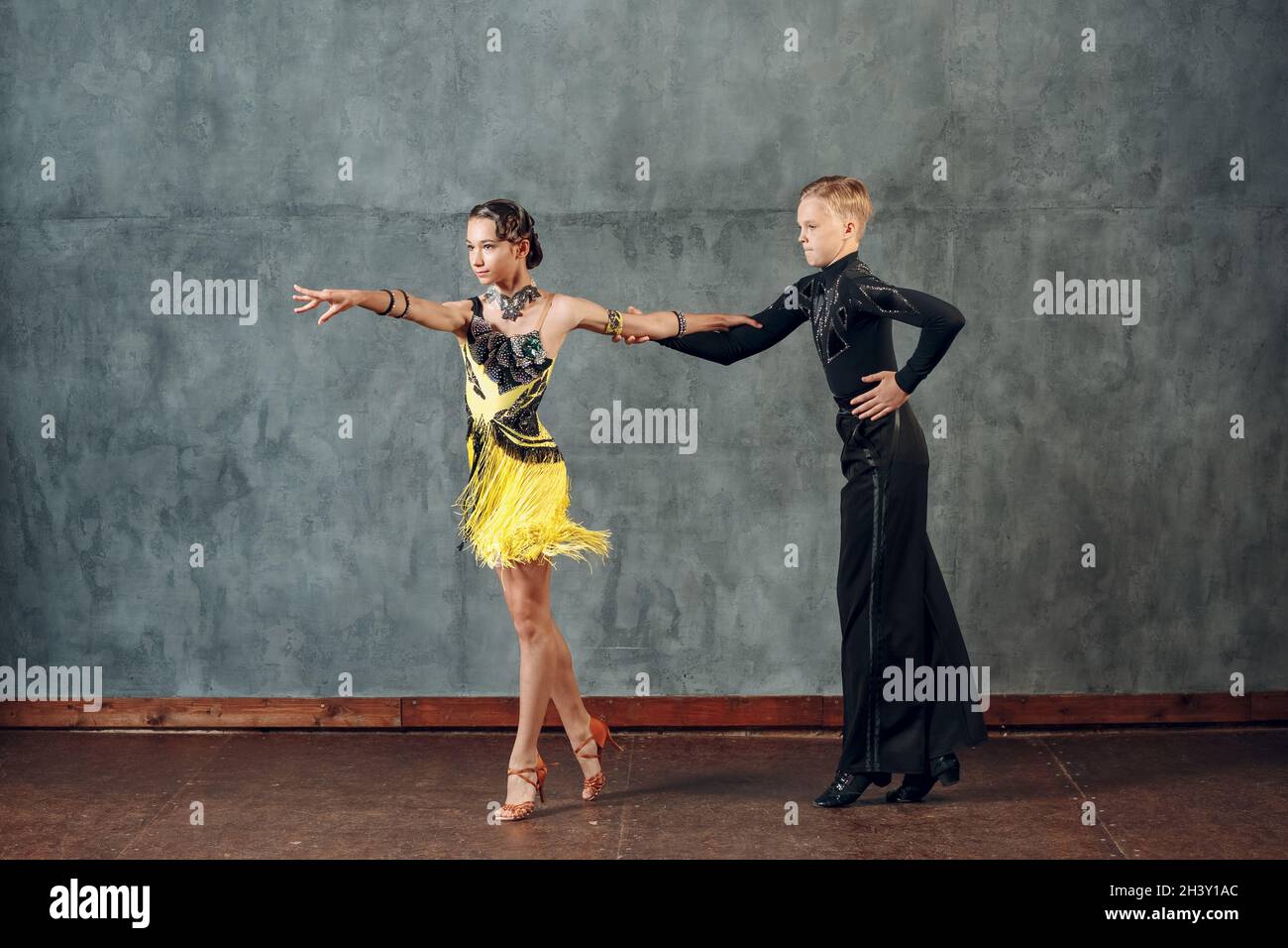 Tanzsamba im Ballsaal. Junges Paar in gelben und schwarzen Kostümen tanzend. Stockfoto