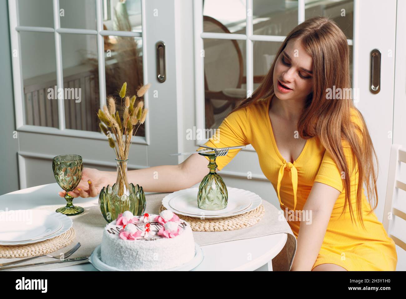 Junge einsame Frau sitzt und langweilig allein zu Hause oder im Café mit weißem Geburtstagskuchen Stockfoto