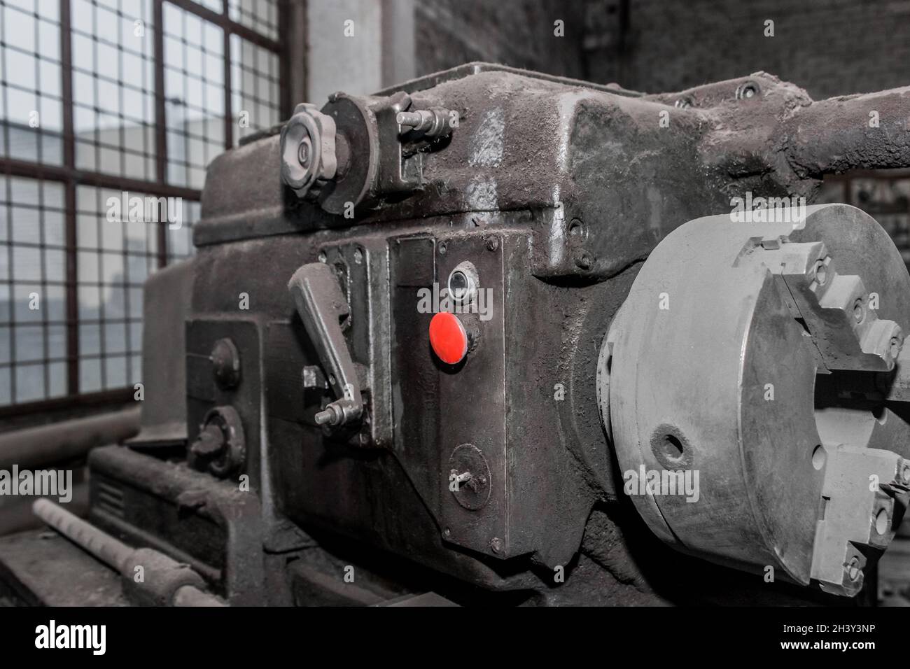Roter Startknopf zur Steuerung der alten Fräsmaschinen-Ausrüstung in der Werkstatt im Industriewerk. Stockfoto