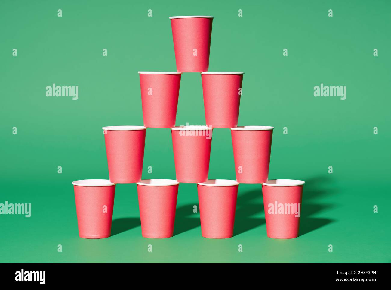 Pyramide aus roten Pappbechern auf grünem Hintergrund Stockfoto