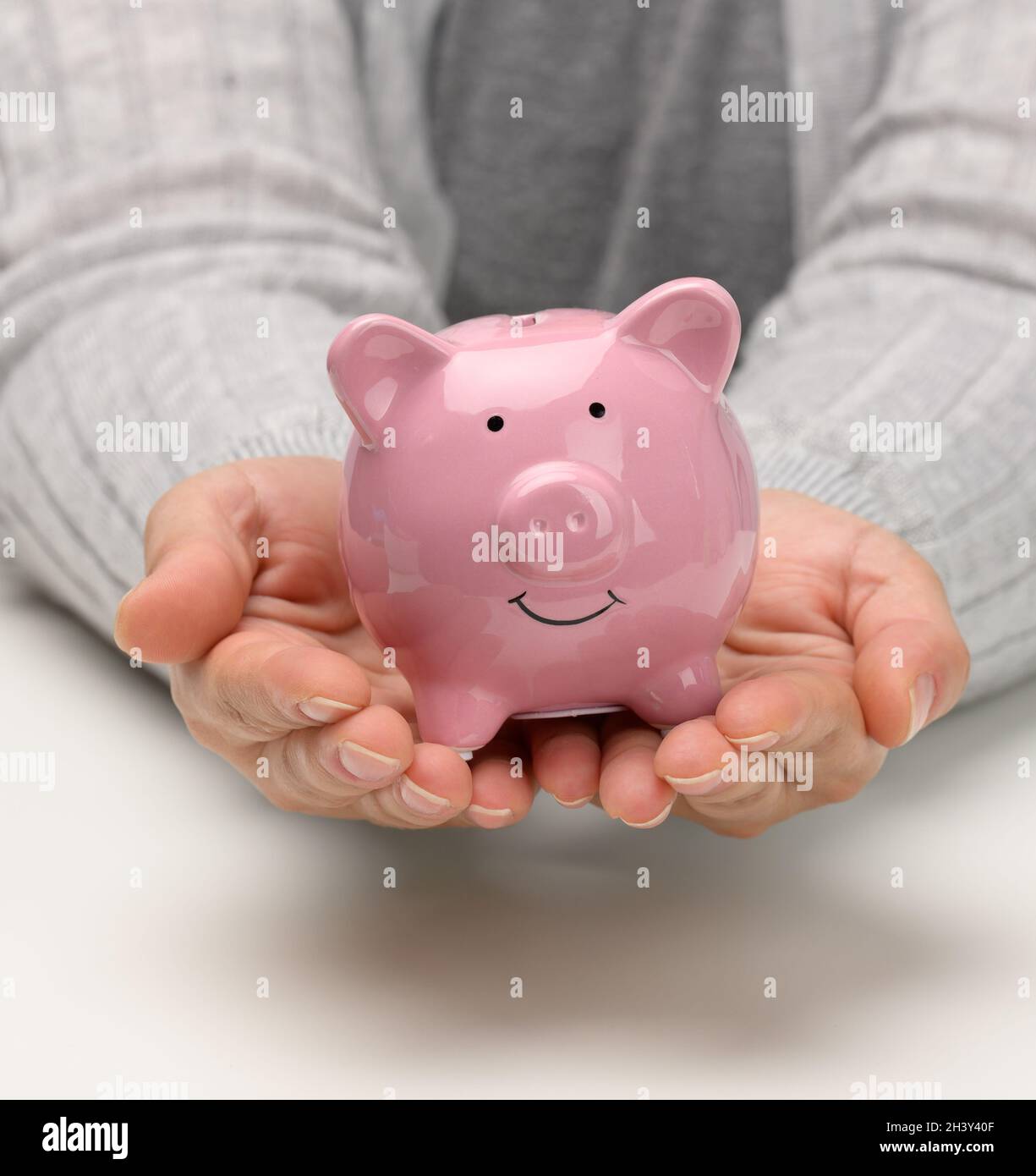 Weibliche Hände halten ein rosa Keramikschwein. Akkumulationskonzept, Budgetkontrolle Stockfoto