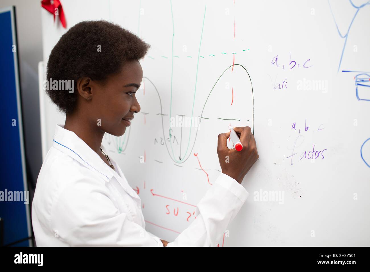 Afroamerikanische Mathematiklehrerin steht an der Tafel mit Marker Stockfoto