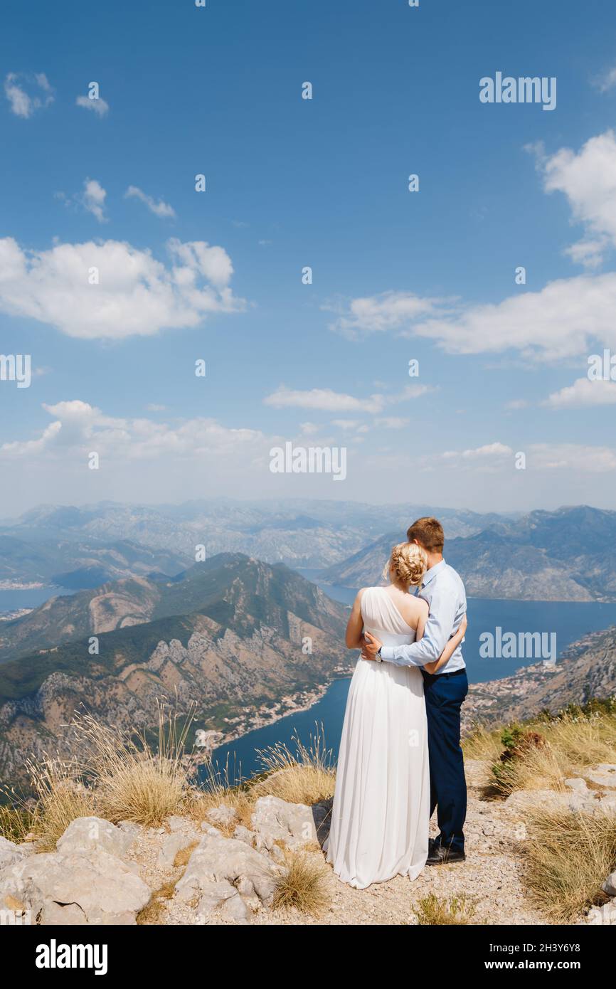 Ein Mann und eine Frau umarmen sich auf dem Berg Lovcen, vor ihnen öffnet sich ein Panoramablick auf die Bucht von Kotor Stockfoto
