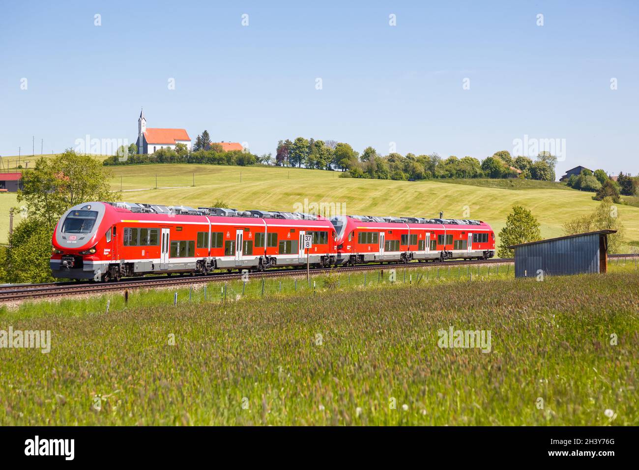 Pesa Link Regionalzug der Deutschen Bahn DB in Aitrang Bayern mit Kirche St. Alban in AllgÃ¤U Deutschland Stockfoto