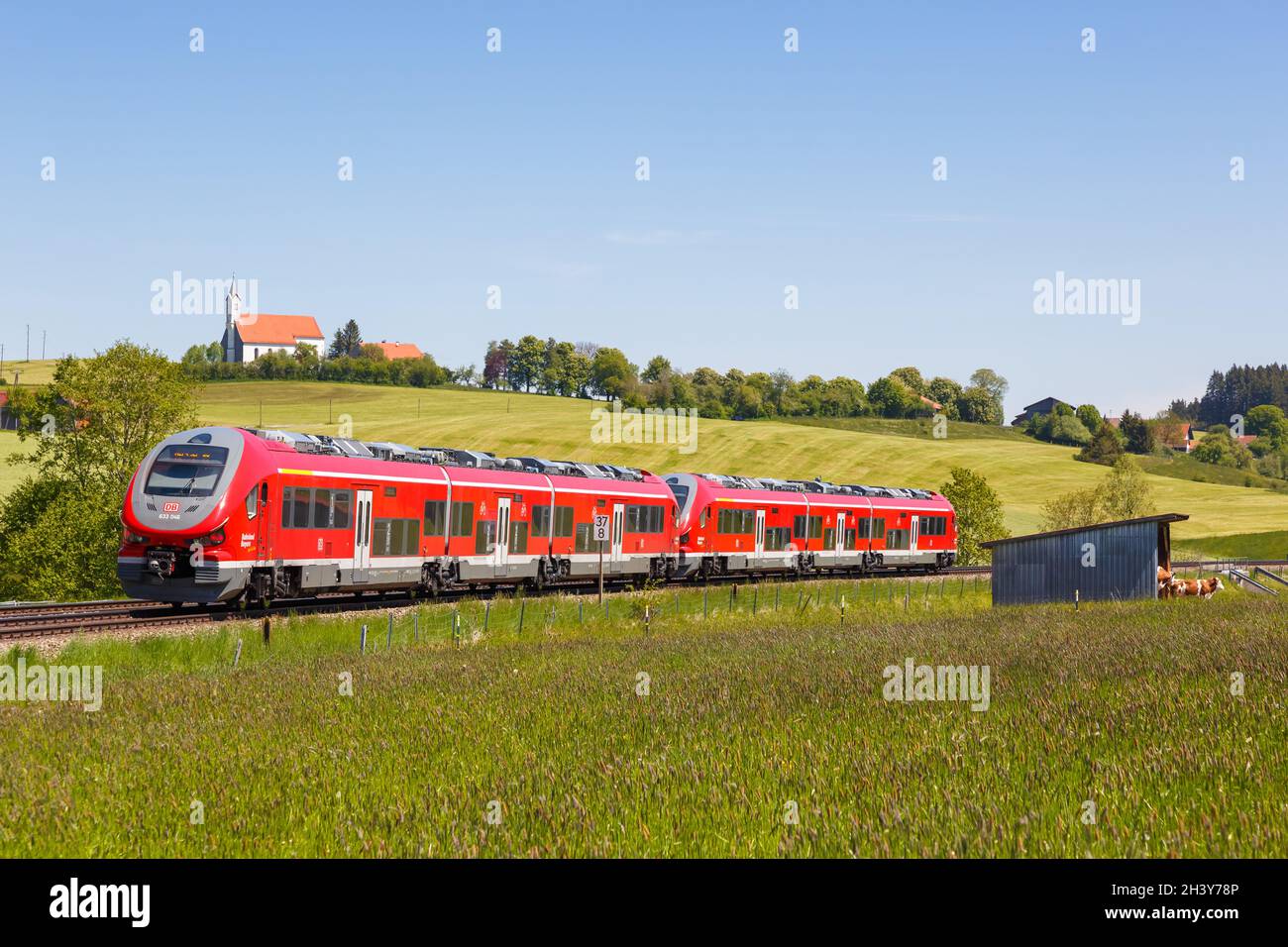 Pesa Link Regionalzug der Deutschen Bahn DB in Aitrang Bayern mit Kirche St. Alban in AllgÃ¤U Deutschland Stockfoto