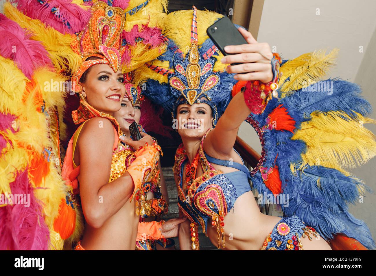 Frau im brasilianischen Samba Karnevalskostüm mit bunten Federn Gefieder mit Handy Selfie im alten Eingang mit großen nehmen Stockfoto