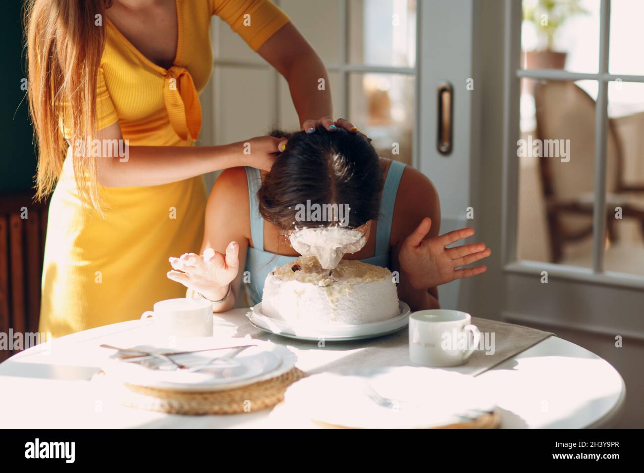 Junge Frau taucht Gesicht in weißen Kuchen mit Sahne. Happy Birthday  Konzept Stockfotografie - Alamy
