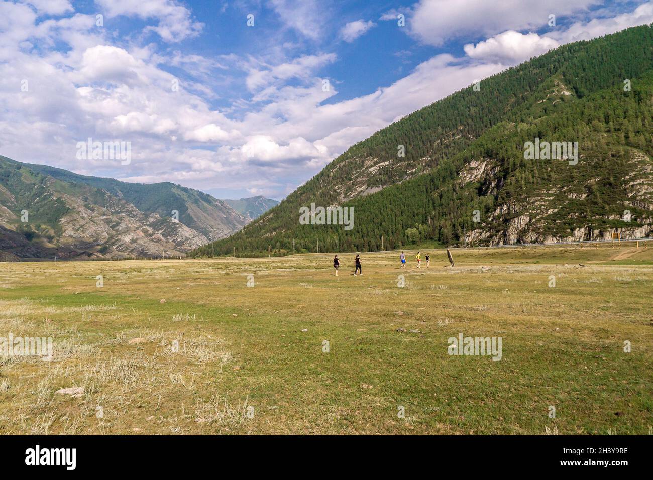 Die Menschen wandern von den Felsmalereien des Kalbak-Tash-Traktes vorbei am Chuisky Deer Stone zum Chuisky-Trakt im Tal zwischen mit Nadelbäumen bewachsenen Bergen Stockfoto