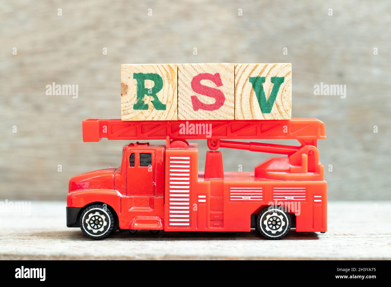 Feuerleiter LKW halten Buchstabenblock in Wort RSV (Abkürzung von Respiratory Syncytial Virus) auf Holz Hintergrund Stockfoto