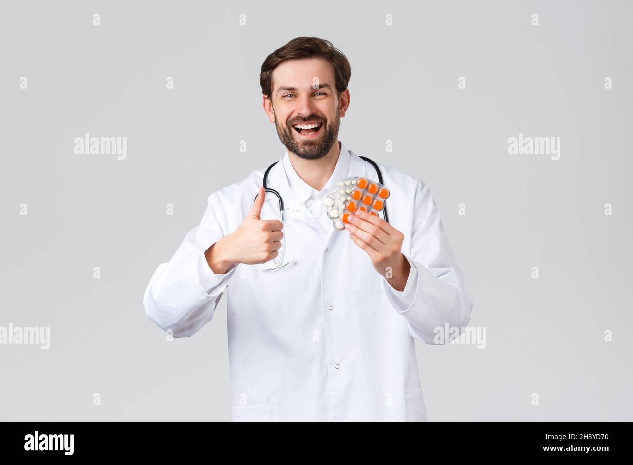 Krankenhaus, medizinisches Personal, covid-19 Behandlungskonzept. Glücklich fröhlich kaukasischen Arzt lächelt, zeigen Daumen-up in Zustimmung und Stockfoto