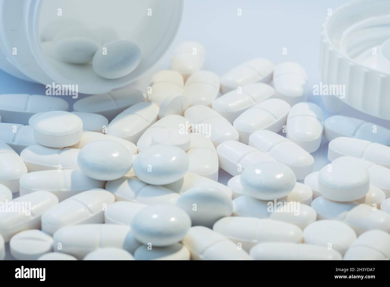 Helsinki / Finnland - 31. OKTOBER 2021: Nahaufnahme von weißen Pillen vor weißem Hintergrund. Weißer Pillenbehälter im Hintergrund. Stockfoto