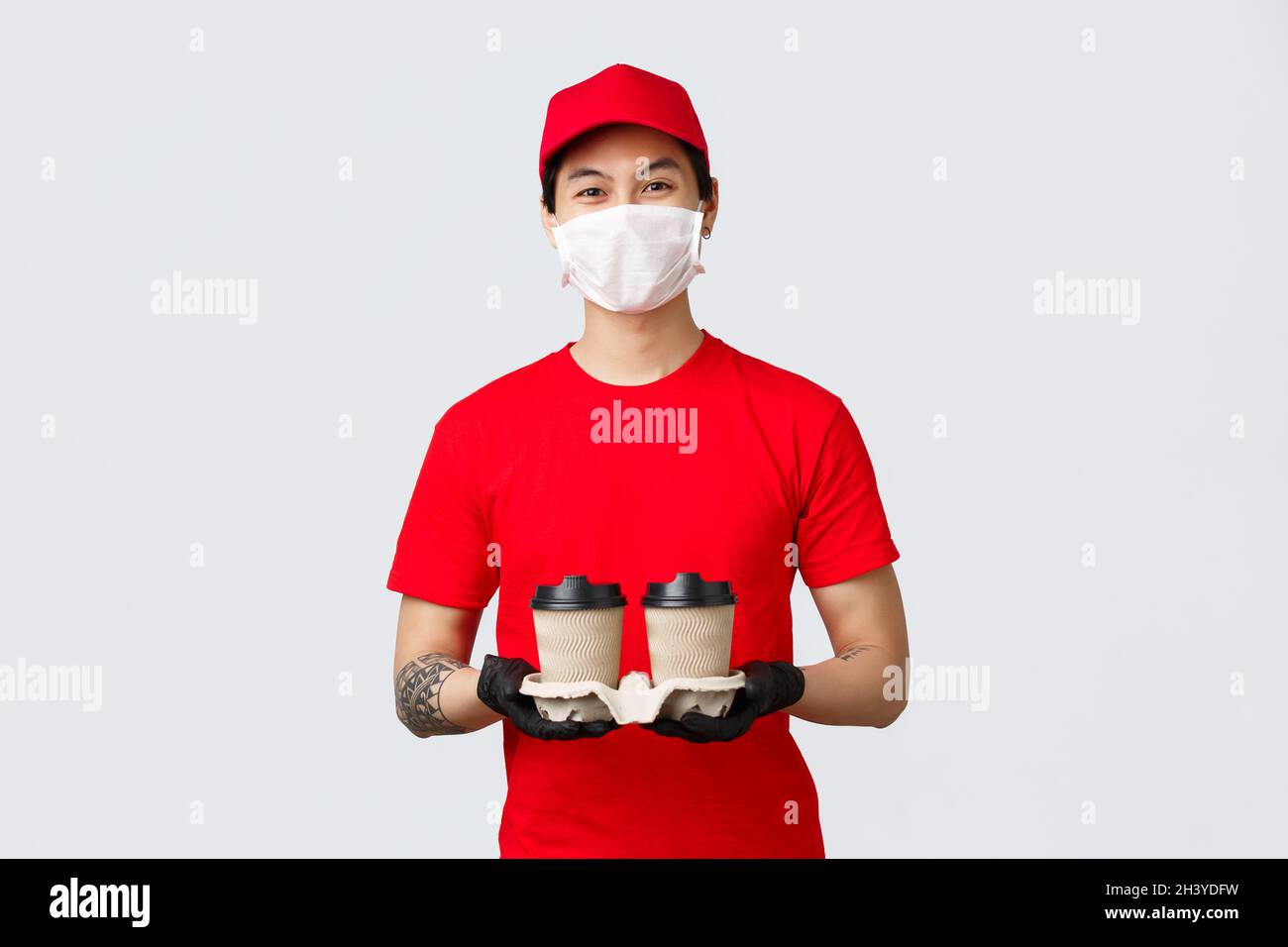 Asiatische Lieferung Kerl bringen Kaffee zu Ihrer Haustür von Lieblings-Café während covid 19 Pandemie Quarantäne, Selbstisolierung. C Stockfoto