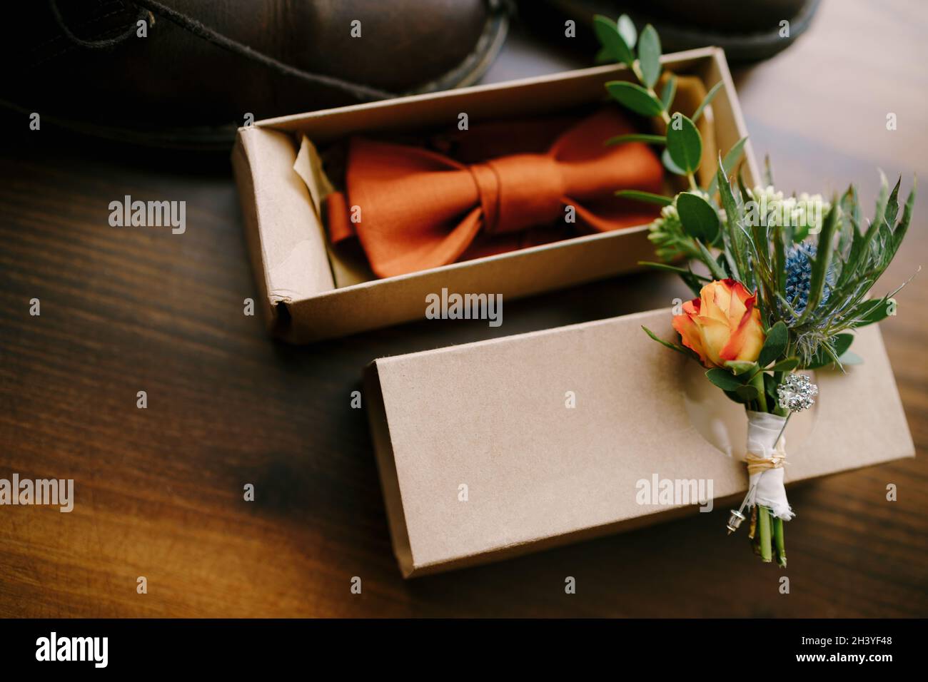 Orange Fliege in einem Geschenkpaket mit einer Knospe für den Bräutigam. Stockfoto