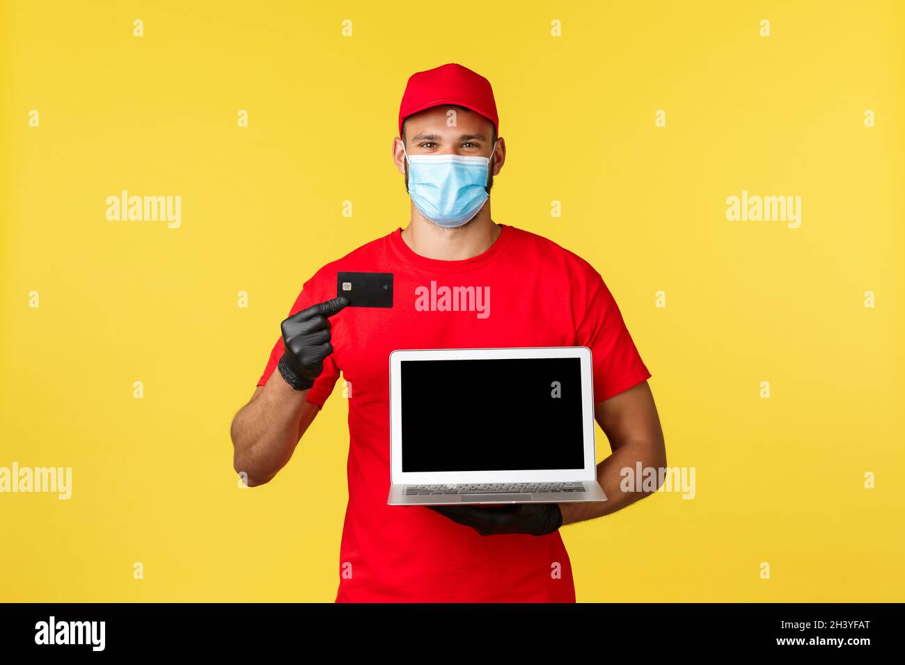Covid-19, sicheres Einkaufen, Express-Lieferung und Auftragsverfolgung Konzept. Lächelnder Kurier in medizinischer Maske, Uniform, zeigt Kredit c Stockfoto