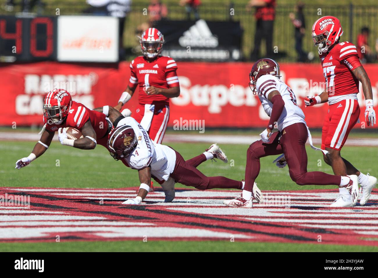 Louisiana-Lafayette Ragin Cjuns läuft zurück Montrell Johnson (4) stürzt nach vorne, als er von Troy Lefeged, einem defensiven Rückenverteidiger der Texas State Bobcats, in Angriff genommen wird Stockfoto