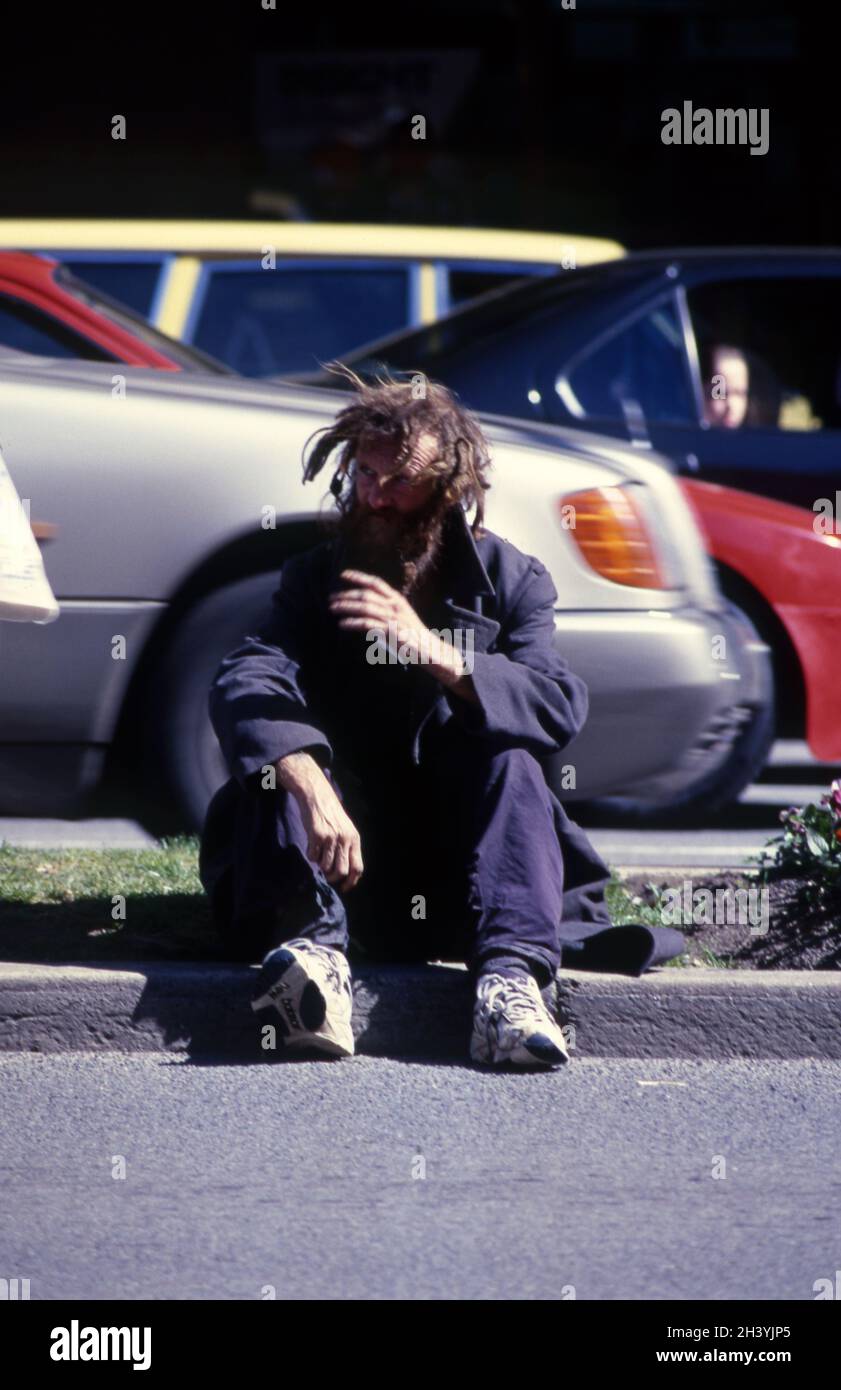 EIN OBDACHLOSER SITZT AM STRASSENRAND, ADELAIDE, SOUTH AUSTRALIA. Stockfoto