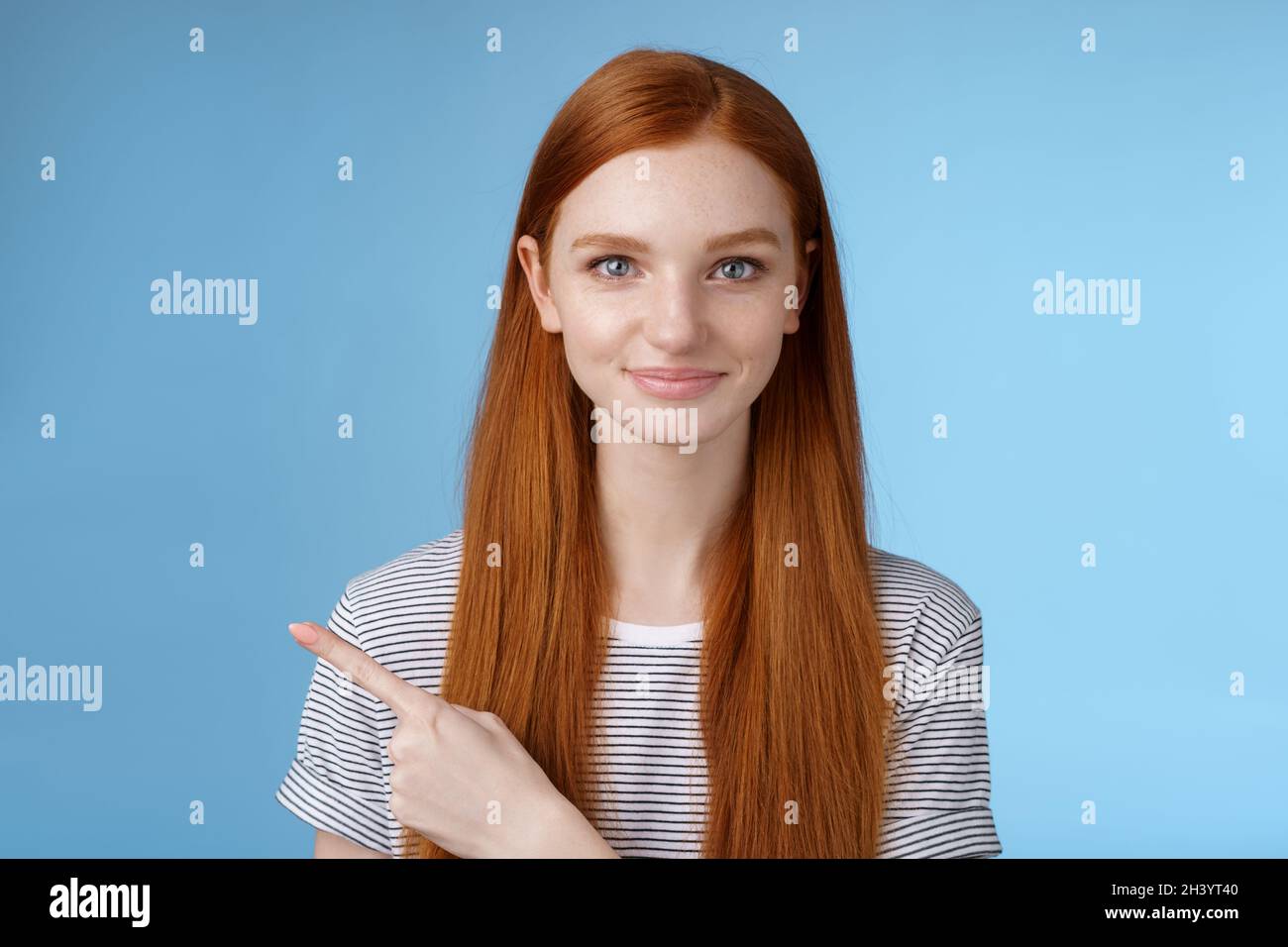 Attraktive bescheiden gut aussehende Rotschopf Freundin handeln reifen freundlich lächeln zeigen linken Zeigefinger geben Richtung sho Stockfoto