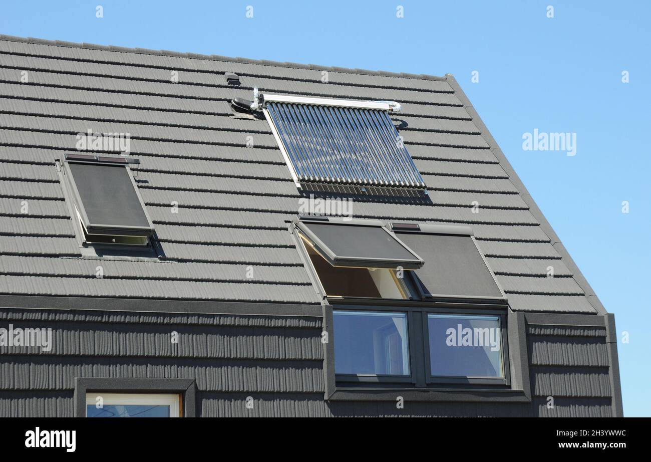 Modernes Dachgeschoss mit Solarmodulen, Oberlichtern und Jalousien für Sonnenschutz und Energieeffizienz des Hauses. Stockfoto
