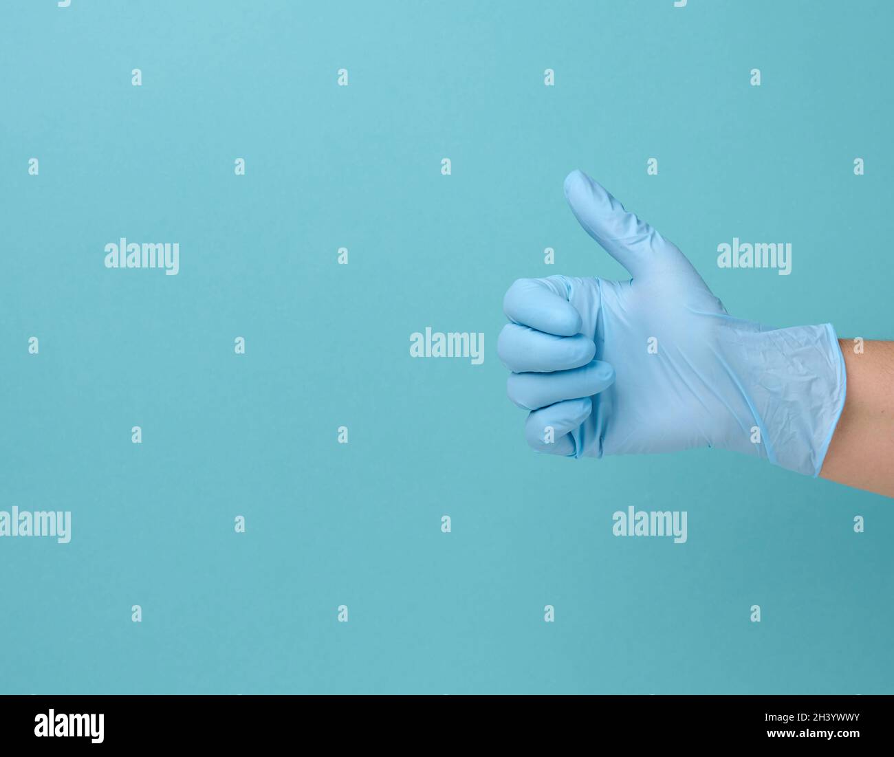 Hand in einem blauen medizinischen Einweghandschuh aus Latex zeigt die Geste wie auf einem blauen Hintergrund Stockfoto