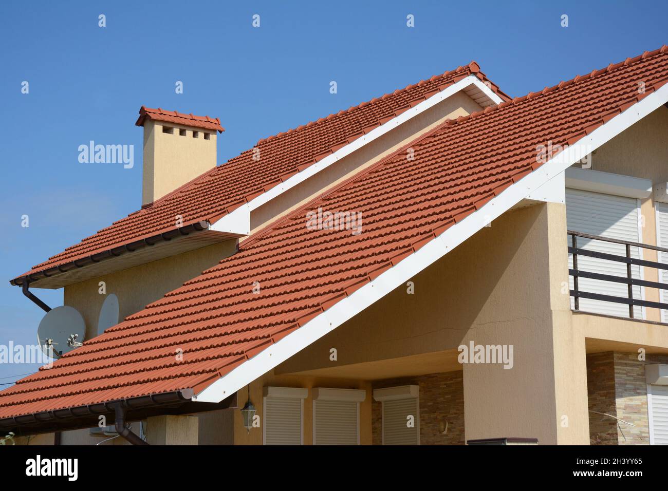Haus mit Lehmziegeldach, Regenrinne, Kamin, Giebel und Tal Art der Dachkonstruktion. Gebäude Dachgeschosshausbau mit Dachziegeln und dif Stockfoto