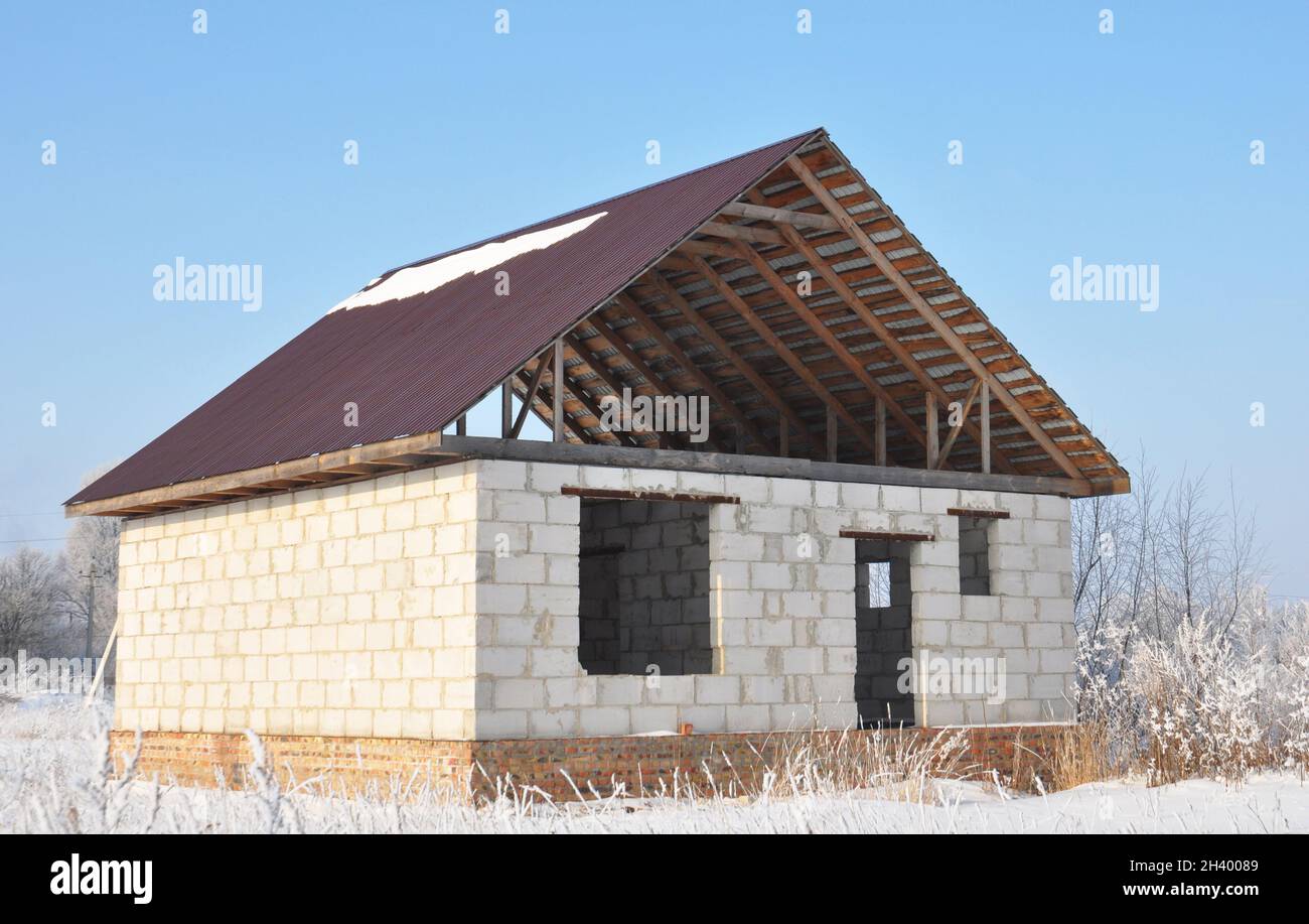Bau eines Hauses mit einem Metalldach, Traversen, Sparren im Winter. Stockfoto