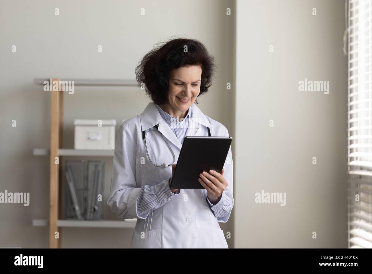 Lächelnde alte Ärztin mit digitalem Tablet. Stockfoto