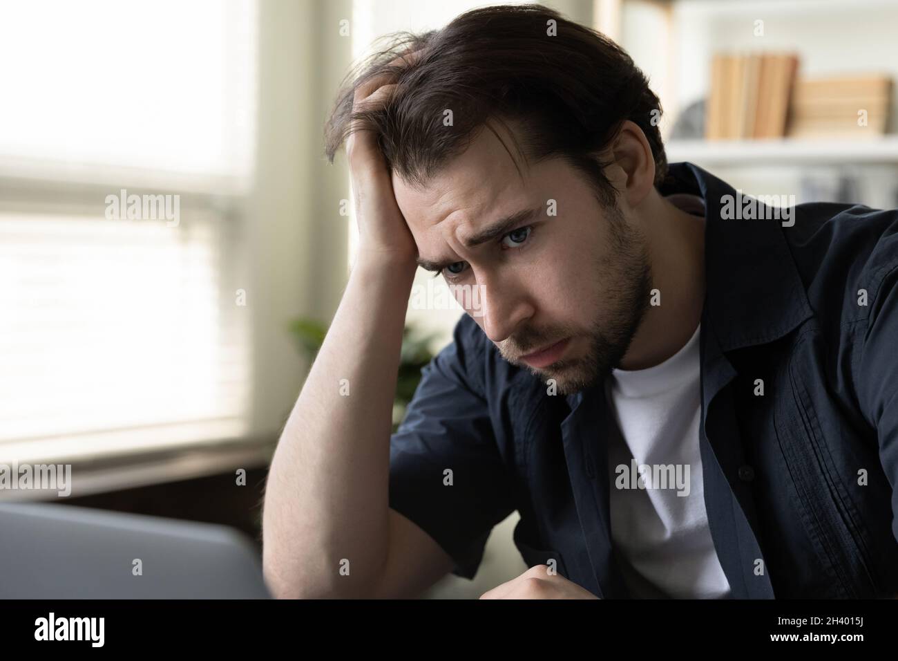 Gestresste unglückliche junge männliche Arbeiter fühlen sich im Büro erschöpft. Stockfoto