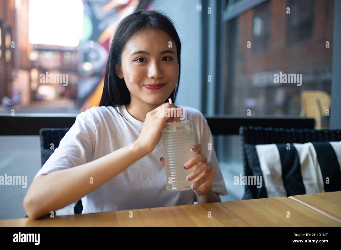 Asiatische junge Frau trinkt Limonadensoda im Café im Freien Stockfoto
