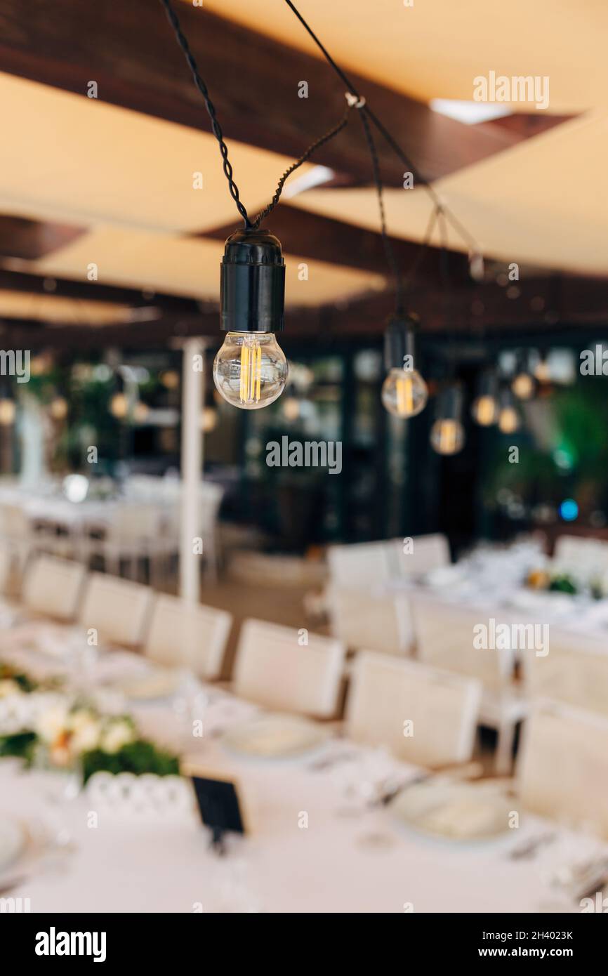 Girlanden von LED-Lampen über einem Bankettisch für ein Hochzeitsessen. Stockfoto