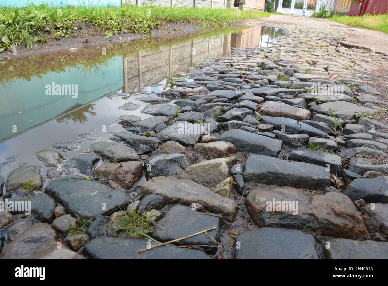 Alte graue gepflasterte Straße mit Pfützen in der alten europäischen Stadt. Stockfoto