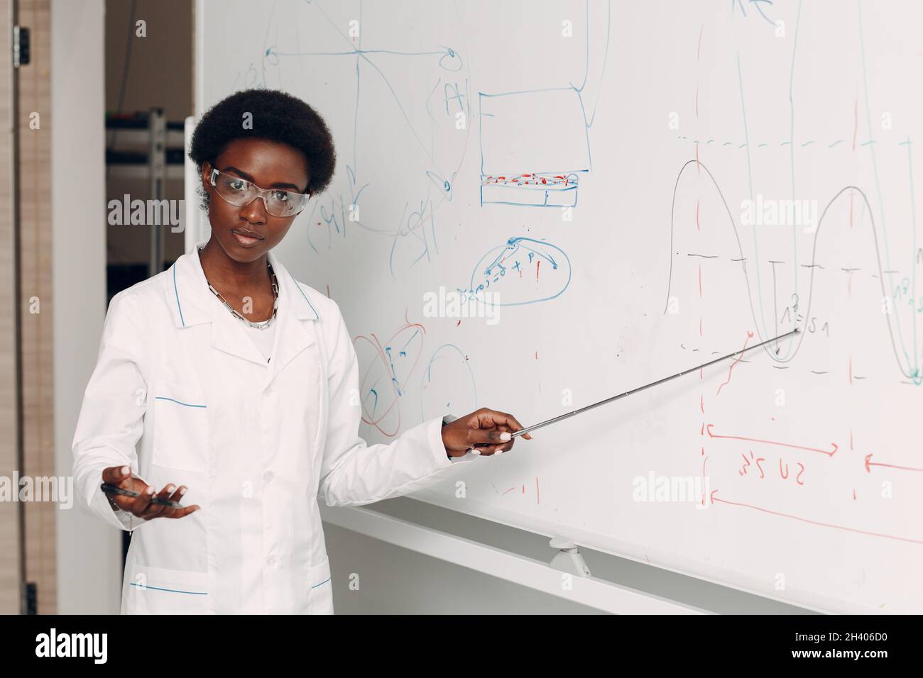 Afroamerikanische Mathematiklehrerin steht an der Tafel mit Zeiger Stockfoto