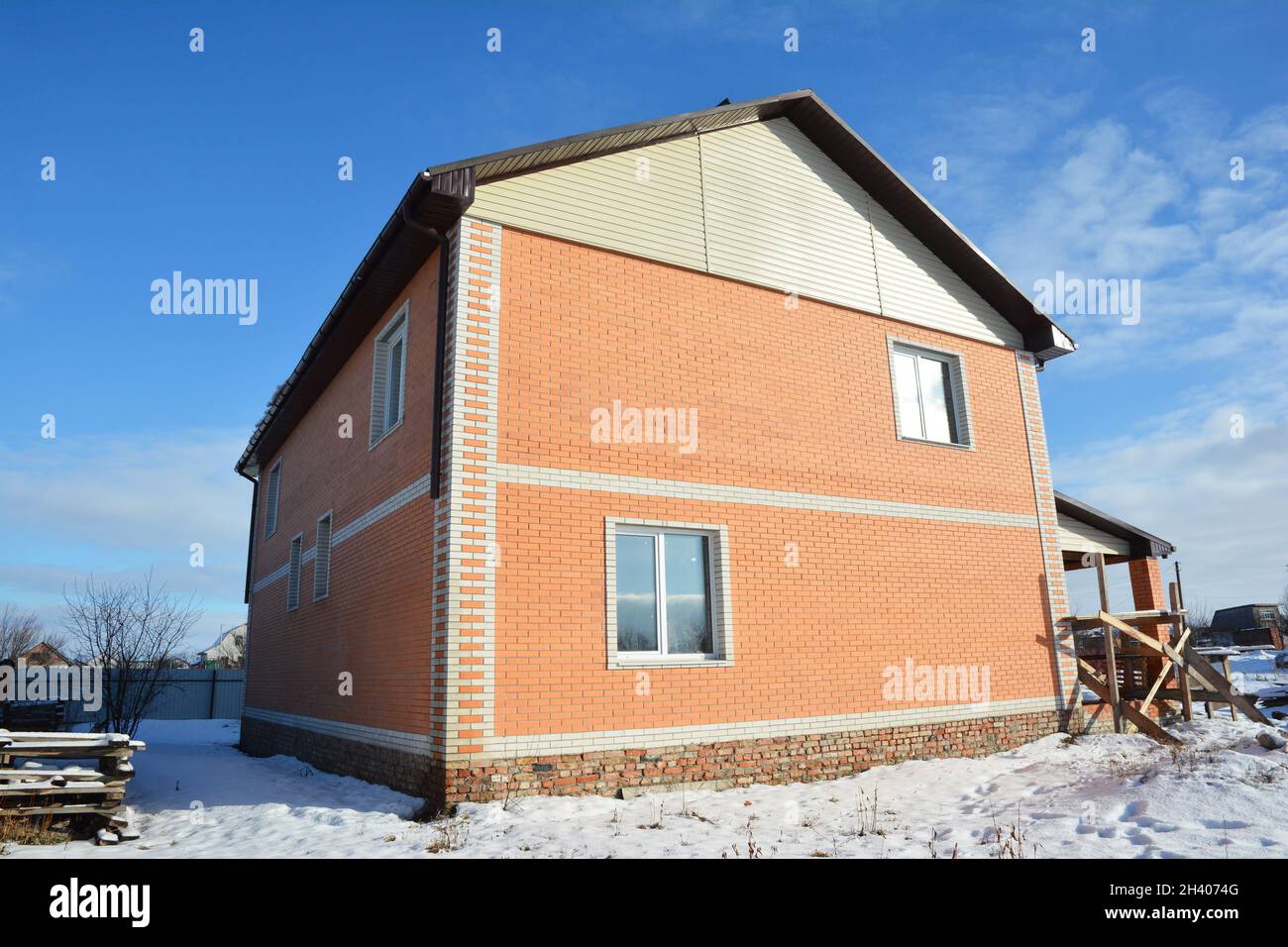 Ein einfaches Backsteinhaus mit einem Giegeldach im Winter im Bau. Stockfoto